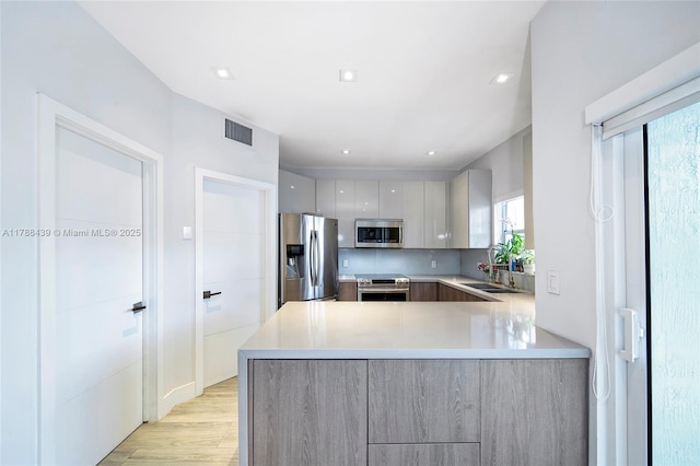 381 Franklin St, Hollywood, FL 33019 - kitchen with a peninsula, a sink, modern cabinets, light countertops, and appliances with stainless steel finishes