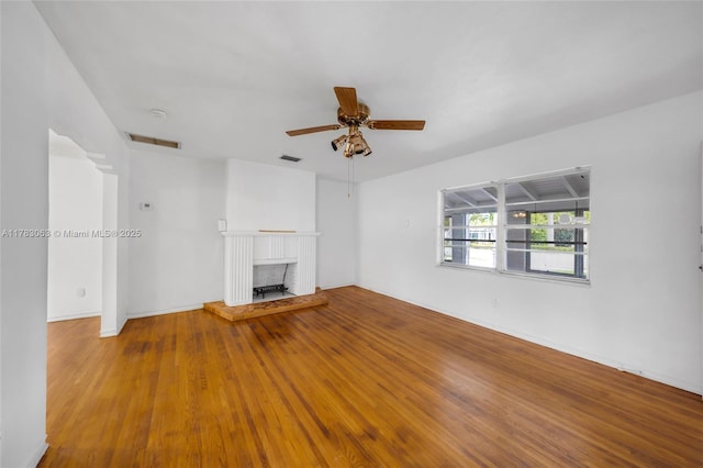 790 NE 96th St, Miami Shores, FL 33138 - unfurnished living room with wood finished floors, a brick fireplace, ceiling fan, and visible vents