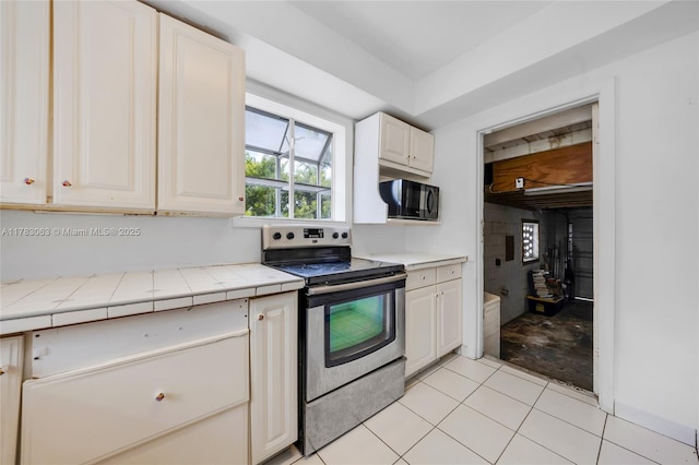 790 NE 96th St, Miami Shores, FL 33138 - kitchen featuring white cabinets, black microwave, electric stove, and light tile patterned floors