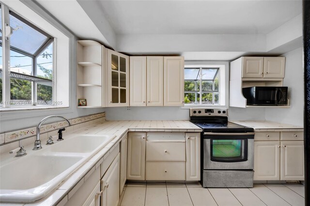 790 NE 96th St, Miami Shores, FL 33138 - kitchen with a sink, stainless steel range with electric cooktop, black microwave, light countertops, and light tile patterned floors