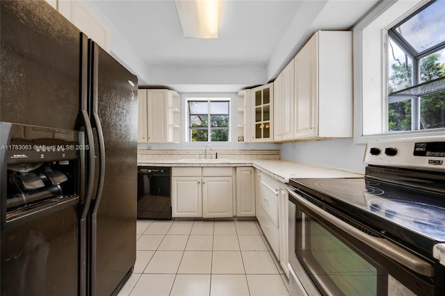 790 NE 96th St, Miami Shores, FL 33138 - kitchen featuring light countertops, light tile patterned floors, a sink, black appliances, and glass insert cabinets