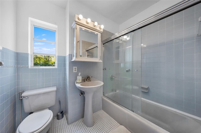 790 NE 96th St, Miami Shores, FL 33138 - bathroom featuring tile patterned floors, wainscoting, tile walls, toilet, and shower / bath combination with glass door