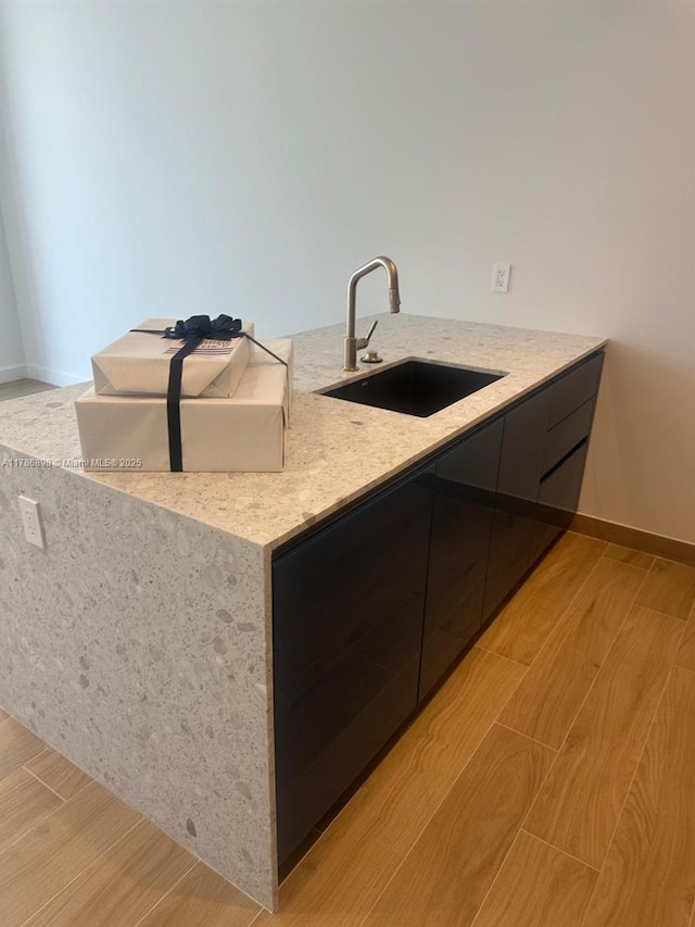 2655 S Bayshore Dr Unit 1607, Miami, FL 33133 - kitchen featuring modern cabinets, a sink, light stone counters, baseboards, and light wood-style flooring
