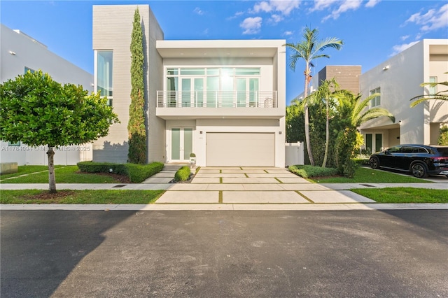 modern home featuring french doors, driveway, an attached garage, and stucco siding