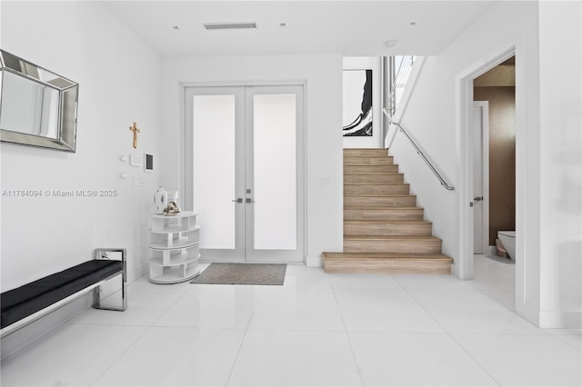 foyer entrance with french doors, visible vents, tile patterned flooring, and stairway