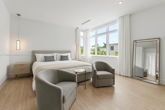 bedroom featuring light wood-style flooring, visible vents, and baseboards