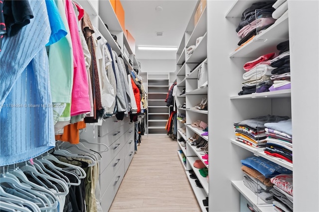 walk in closet with light wood-style floors