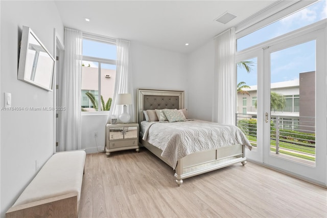 bedroom with visible vents, wood finished floors, and access to outside