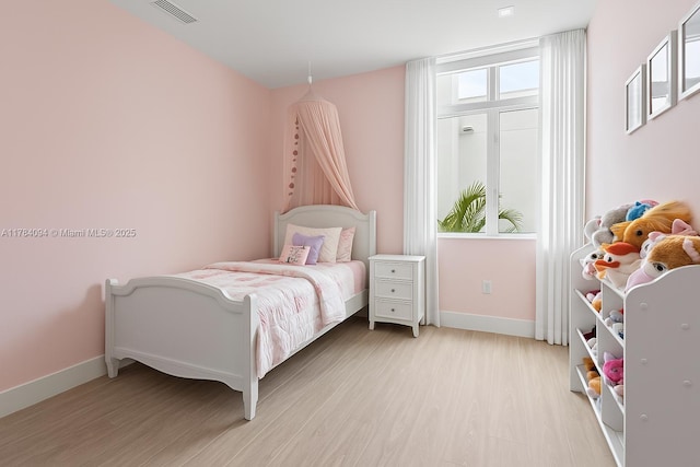 bedroom featuring light wood-type flooring, visible vents, and baseboards