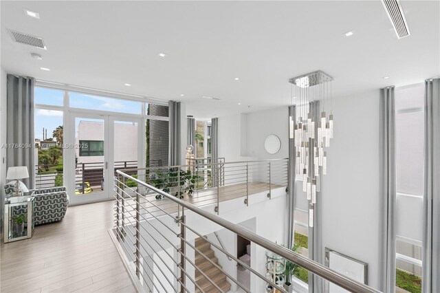 hallway with visible vents, a healthy amount of sunlight, and an upstairs landing
