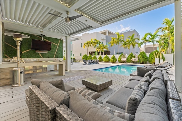 pool featuring outdoor lounge area, a deck, and a ceiling fan