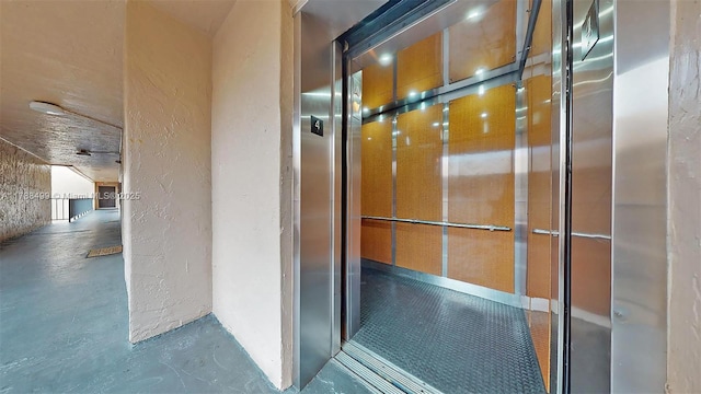 13715 Kendale Lakes Cir Unit Ph-A10, Miami, FL 33183 - interior details featuring a textured wall, elevator, and finished concrete floors