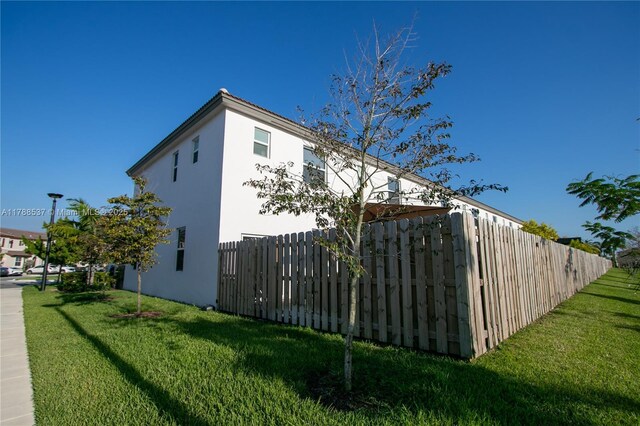 view of property exterior featuring a lawn, fence, and stucco siding