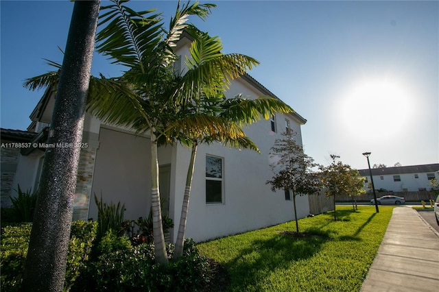 view of side of property with stucco siding and a yard