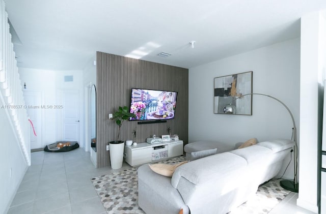 living room featuring an accent wall, visible vents, and light tile patterned floors
