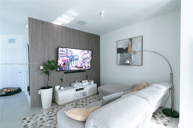 living room with an accent wall, light tile patterned flooring, and visible vents