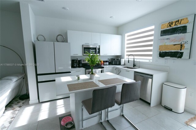 kitchen featuring a sink, light countertops, white cabinets, appliances with stainless steel finishes, and a kitchen island