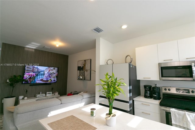 kitchen featuring open floor plan, light countertops, white cabinets, appliances with stainless steel finishes, and visible vents