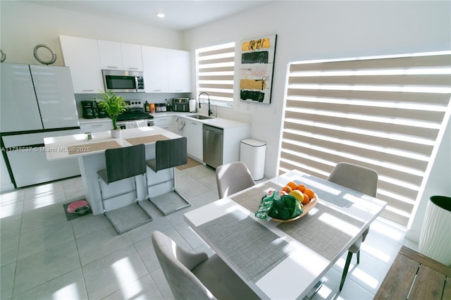 kitchen featuring light countertops, a sink, a center island, appliances with stainless steel finishes, and white cabinetry