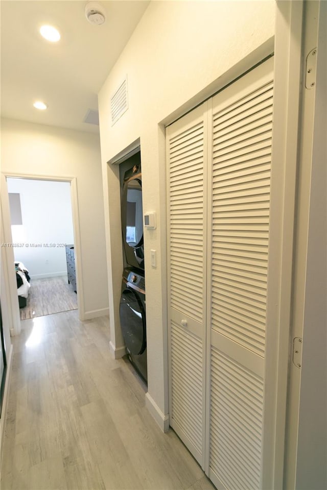hall featuring light wood finished floors, baseboards, recessed lighting, visible vents, and stacked washer and clothes dryer
