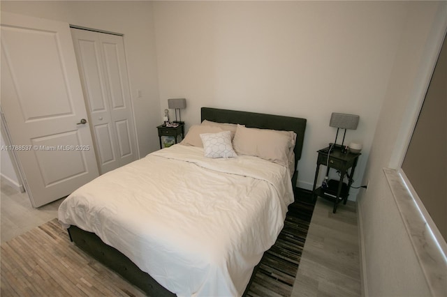 bedroom with baseboards, wood finished floors, and a closet