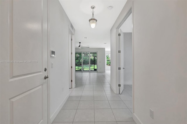 hall featuring baseboards and light tile patterned floors