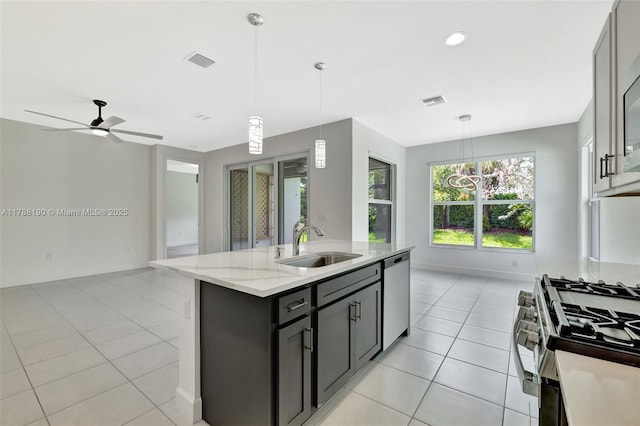 kitchen with a sink, stainless steel appliances, open floor plan, light tile patterned flooring, and a kitchen island with sink