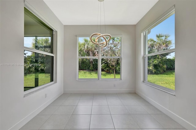unfurnished dining area featuring plenty of natural light, a chandelier, and baseboards