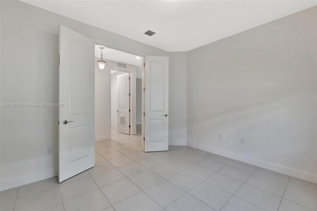 empty room featuring baseboards and light tile patterned flooring