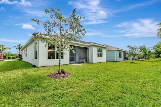 rear view of property with a yard, stucco siding, and a sunroom