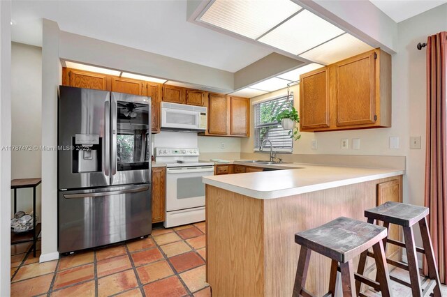 17068 Traverse Cir, Jupiter, FL 33477 - kitchen featuring white appliances, a sink, a peninsula, light countertops, and brown cabinets