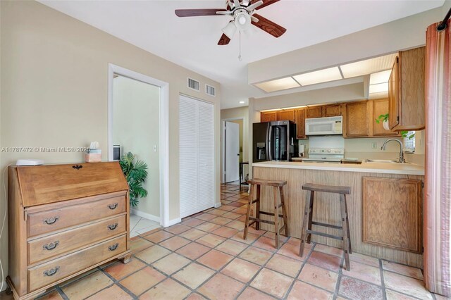 17068 Traverse Cir, Jupiter, FL 33477 - kitchen with white appliances, a sink, ceiling fan, a peninsula, and light countertops