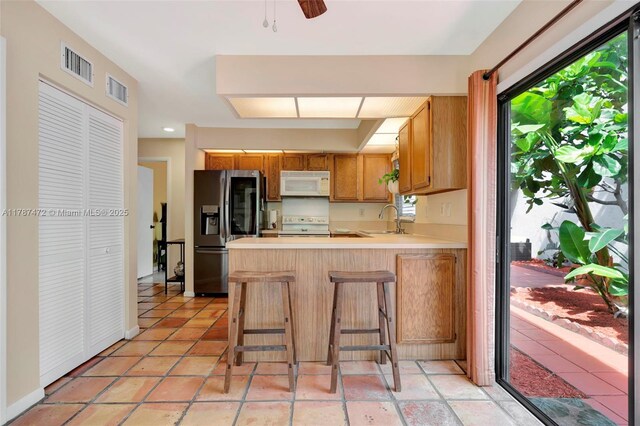 17068 Traverse Cir, Jupiter, FL 33477 - kitchen with white appliances, a sink, a peninsula, light countertops, and a ceiling fan