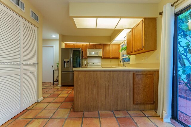 17068 Traverse Cir, Jupiter, FL 33477 - kitchen with white microwave, a peninsula, stainless steel fridge with ice dispenser, range, and light countertops