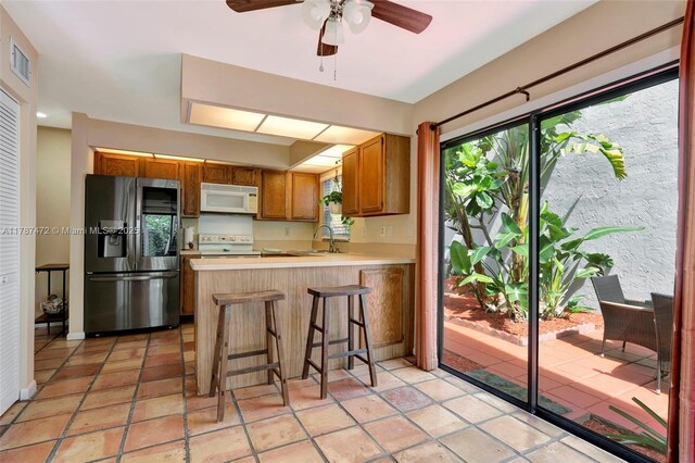 17068 Traverse Cir, Jupiter, FL 33477 - kitchen with white appliances, a sink, light countertops, brown cabinets, and a peninsula