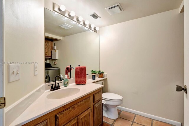 17068 Traverse Cir, Jupiter, FL 33477 - bathroom with washer / dryer, toilet, vanity, tile patterned flooring, and baseboards