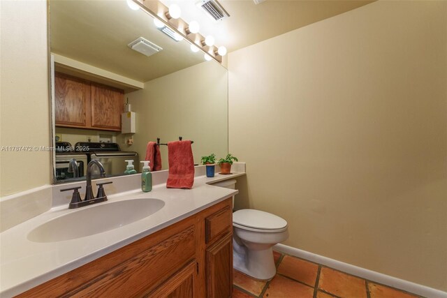 17068 Traverse Cir, Jupiter, FL 33477 - half bathroom featuring washing machine and dryer, toilet, vanity, tile patterned floors, and baseboards