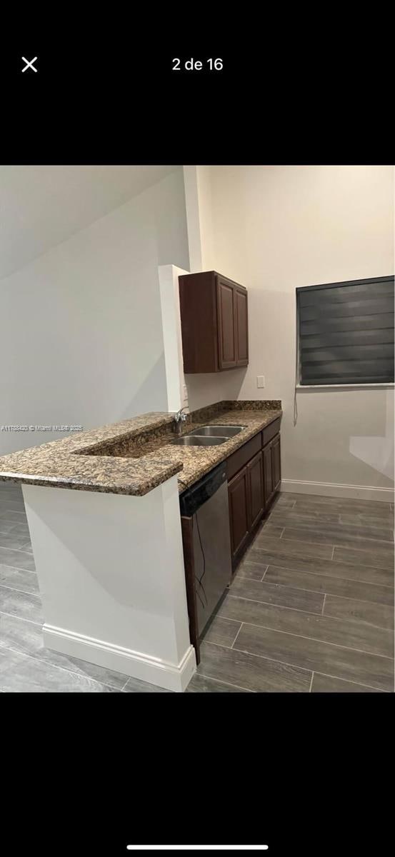 kitchen featuring dishwasher, a sink, baseboards, wood tiled floor, and a peninsula