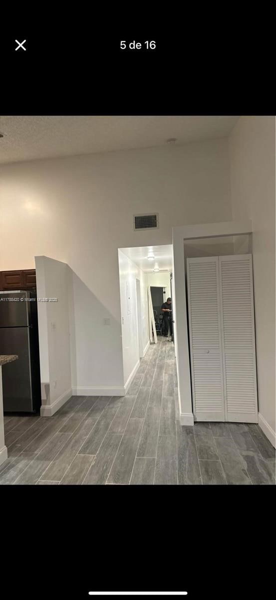 hallway with wood finished floors, visible vents, and baseboards