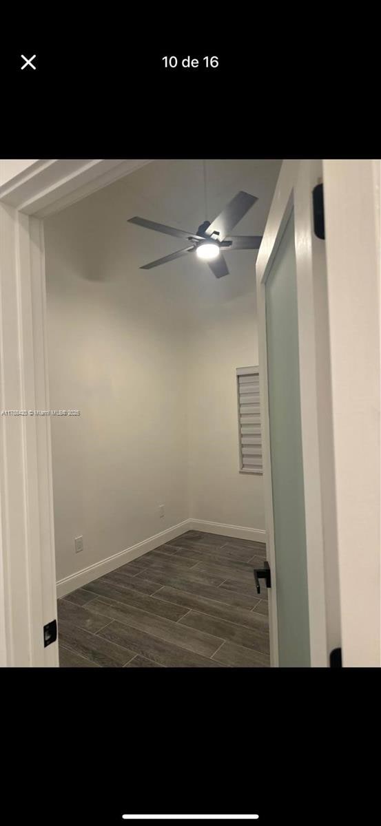 spare room with dark wood-type flooring, a ceiling fan, and baseboards