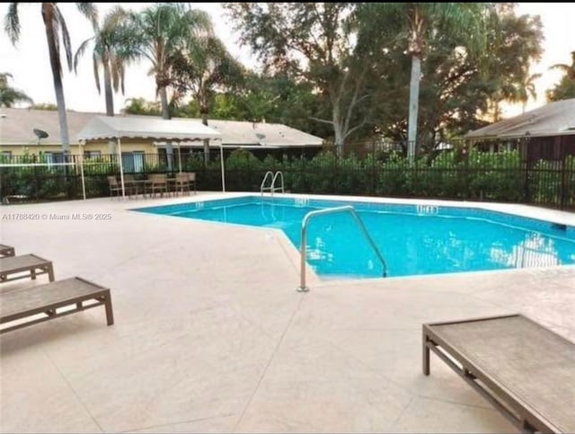 community pool with a patio area and fence