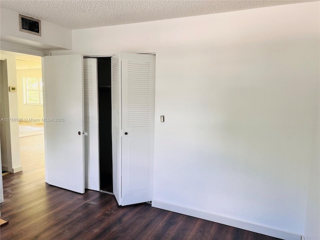 6191 SW 37th St Unit 106, Davie, FL 33314 - unfurnished bedroom featuring dark wood-style flooring, a textured ceiling, visible vents, baseboards, and a closet