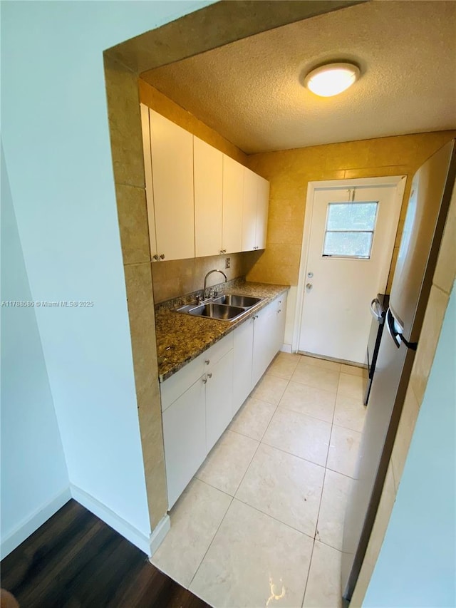 6191 SW 37th St Unit 106, Davie, FL 33314 - kitchen with white cabinets, a textured ceiling, baseboards, and a sink