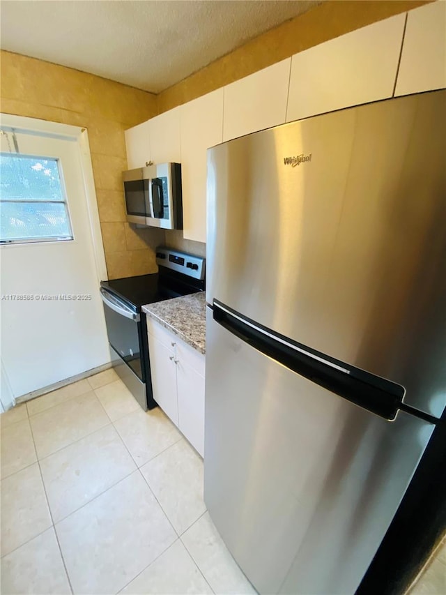 6191 SW 37th St Unit 106, Davie, FL 33314 - kitchen with decorative backsplash, light stone countertops, light tile patterned floors, stainless steel appliances, and white cabinetry