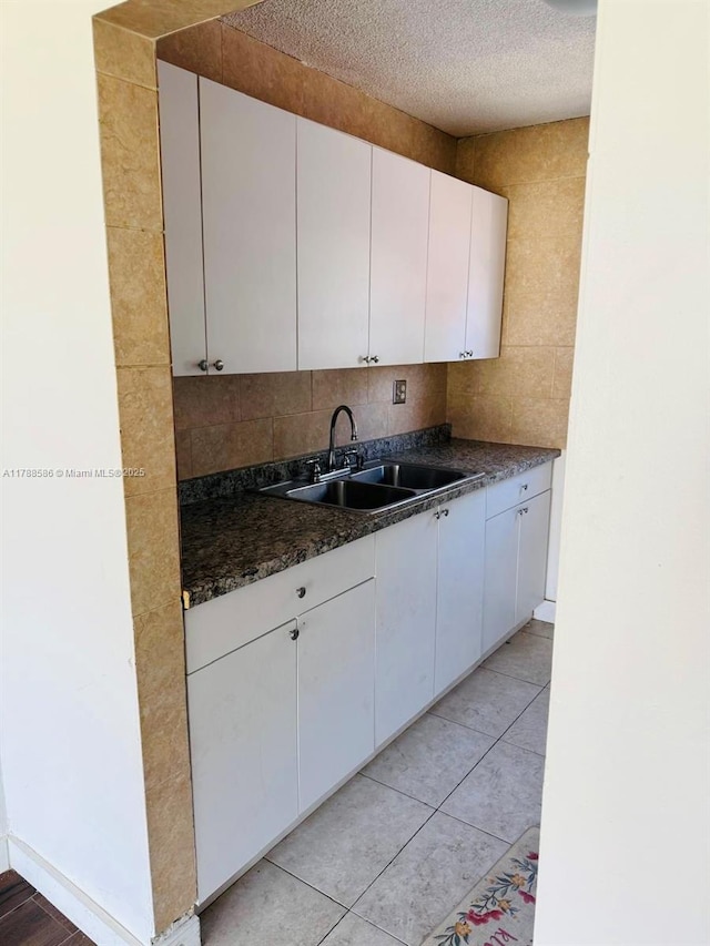 6191 SW 37th St Unit 106, Davie, FL 33314 - kitchen with light tile patterned flooring, dark countertops, a textured ceiling, white cabinets, and a sink