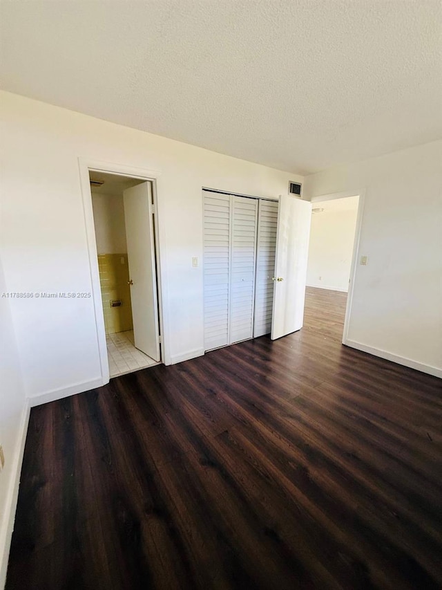 6191 SW 37th St Unit 106, Davie, FL 33314 - unfurnished bedroom featuring a textured ceiling, wood finished floors, baseboards, a closet, and ensuite bath