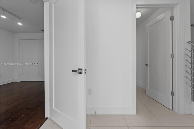 corridor featuring wood finished floors and rail lighting