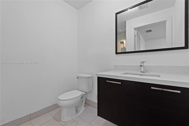 half bath with toilet, vanity, visible vents, and baseboards