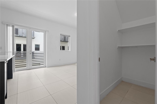 corridor with baseboards and light tile patterned floors