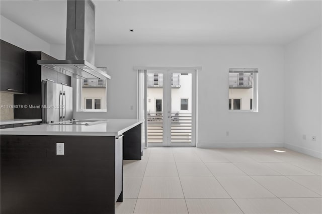 kitchen with island exhaust hood, modern cabinets, dark cabinetry, light countertops, and freestanding refrigerator